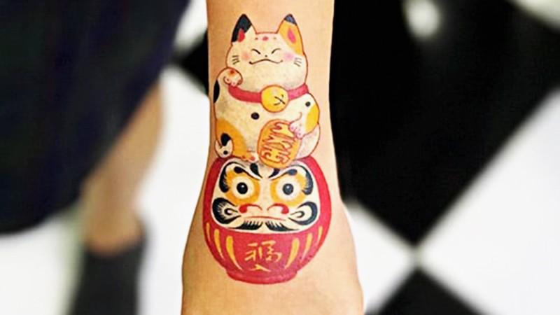 Mèo thần tài ngồi Daruma, hút tài lộc.